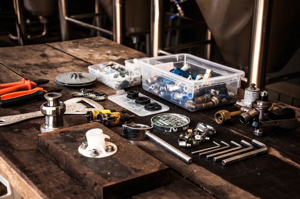 Plumbing fittings, hose clamps, and hex keys sorted into bins on a workbench
