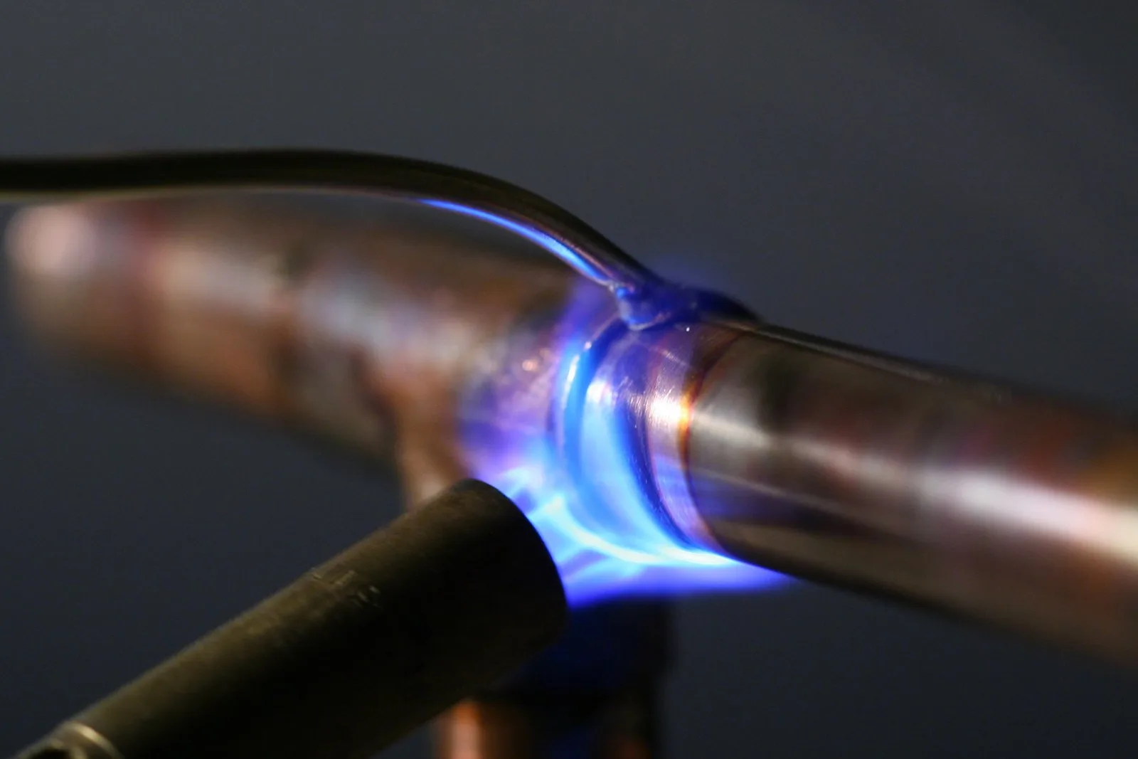 A plumber soldering a copper pipe joint with a propane torch